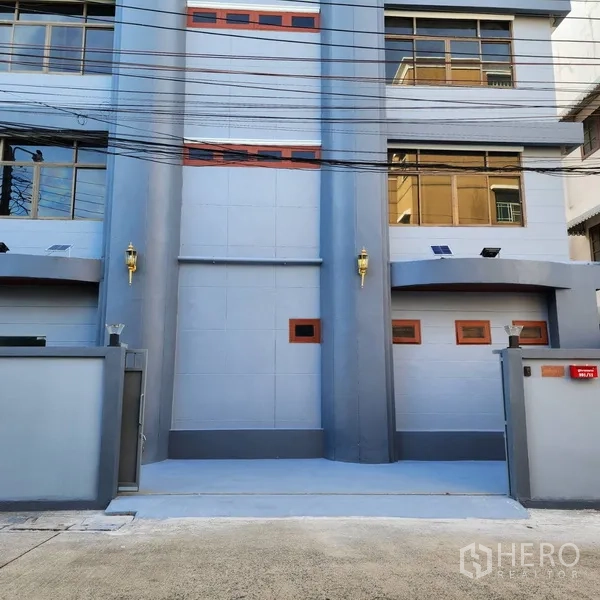 Office Space for rent or sale in Khlong Toei, Bangkok - Close view of the front entrance with twin gray columns, wall lamps, and large windows.
