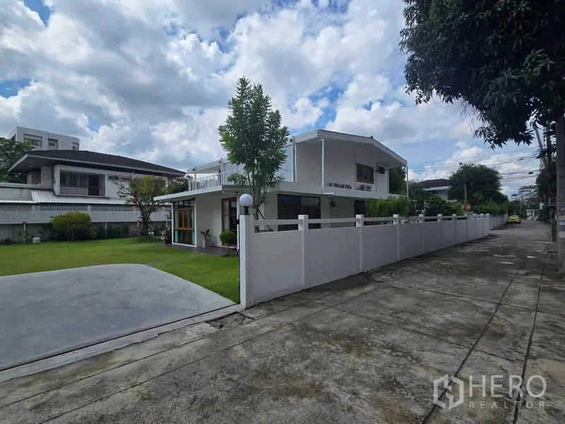 Home Office for rent - Street view of a modern two-storey white home office with a long fence and manicured lawn in Chatuchak.