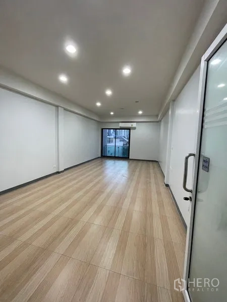 Home Office for rent in Chatuchak, Bangkok - Spacious studio-style room with light wood floor and glass door to balcony.