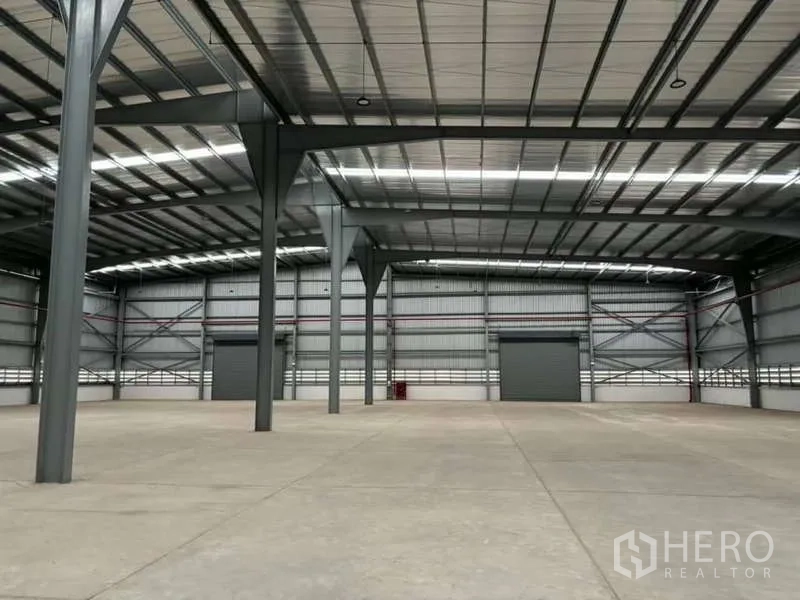 Warehouse for rent in Nikhom Phatthana, Rayong - High-clearance steel-frame warehouse interior with polished concrete floor and large shutter doors