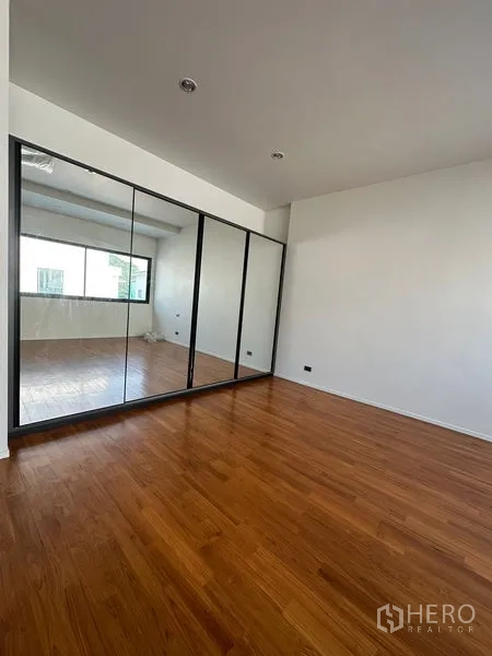 Detached House for rent in Watthana, Bangkok - Bedroom with full-height mirrored wardrobes and polished wooden floor.