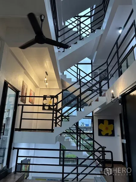 Home Office for rent or sale in Phra Khanong, Bangkok - Open stairwell with black metal railings, ceiling fans and abundant natural light.