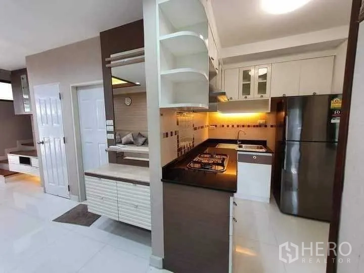 Townhouse for rent in Phra Khanong, Bangkok - Kitchen view with illuminated backsplash, gas cooktop and ample cabinetry.