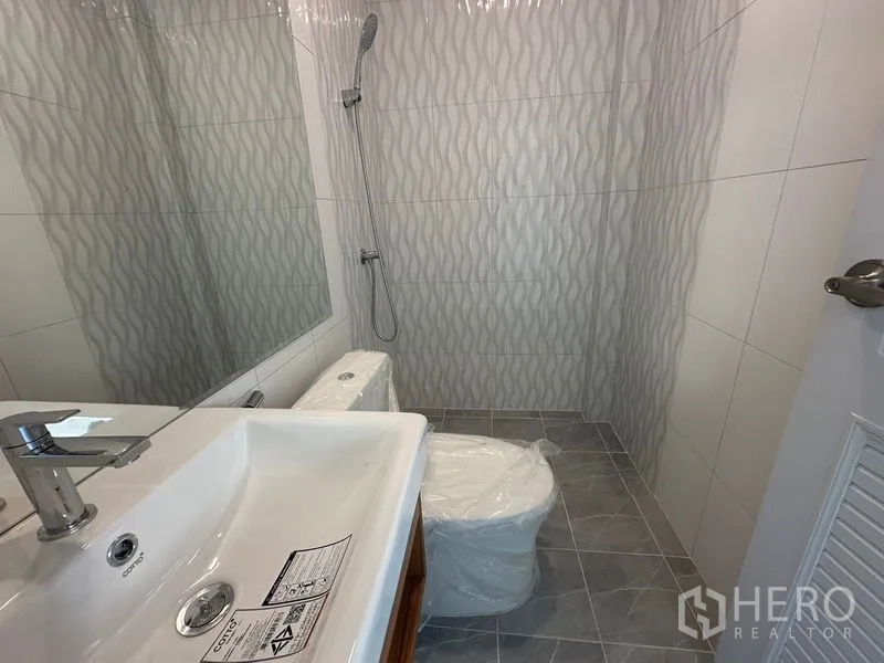 Home Office for rent in Wang Thonglang, Bangkok - Bathroom with wave-pattern wall tiles, vanity, and shower area.