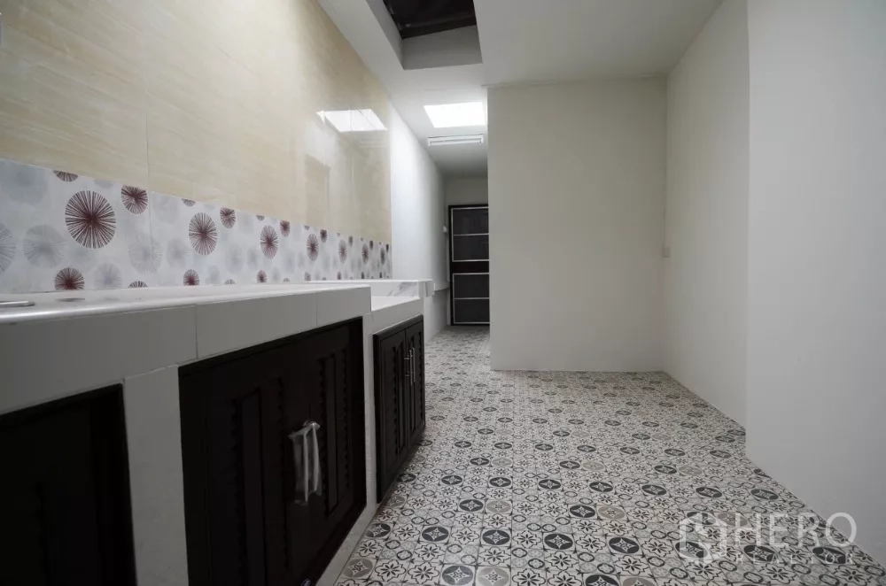 Home Office for rent in Lat Phrao, Bangkok - Galley kitchen with patterned floor tiles, long countertop and under‑counter cabinets.