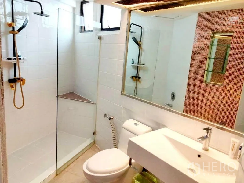Condominium for rent in Khlong Toei, Bangkok - Modern white bathroom with glass-enclosed shower, backlit mirror and sleek fixtures.