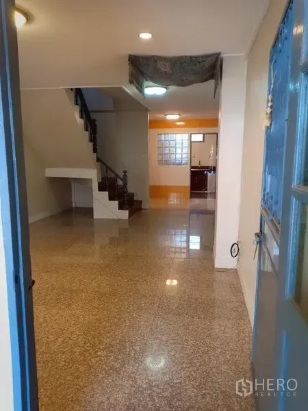 Townhouse for rent in Phra Khanong, Bangkok - Open-plan living area with terrazzo floors, recessed lighting and a staircase to upper levels.