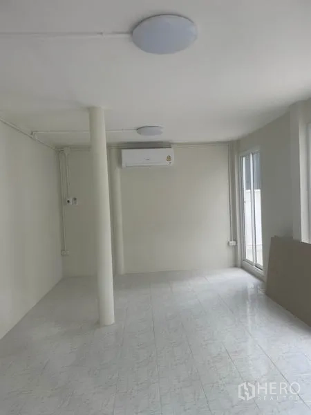 独立式住宅 出租在Huai Khwang, Bangkok - 一层开放式空间，白色地砖、空调与通向露台的推拉门。