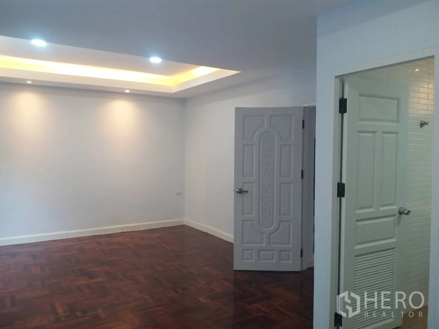 Townhouse for rent in Khlong Toei, Bangkok - Spacious bedroom with parquet flooring, recessed ceiling lights and an ensuite door.
