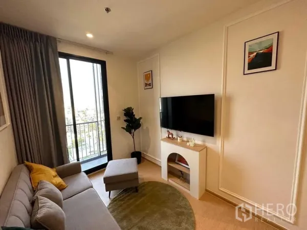 Condominium for sale - Cozy living space with sofa, TV and balcony overlooking the Bangkok skyline.