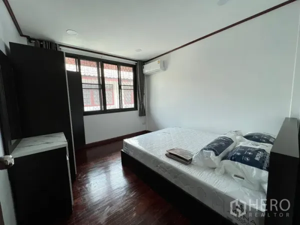 Townhouse for rent in Din Daeng, Bangkok - Air-conditioned bedroom with double bed, large window and dark wood flooring.