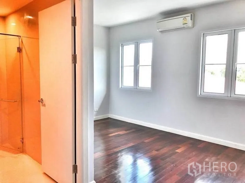 Townhouse for rent in Watthana, Bangkok - Bedroom with two windows beside a glass-enclosed shower room.