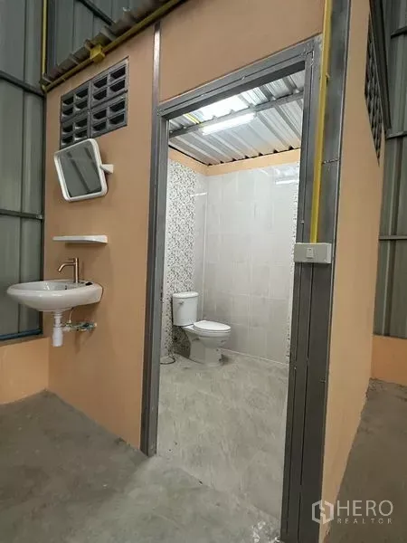 Warehouse for rent in Bueng Kum, Bangkok - Private restroom inside the warehouse featuring a toilet, sink, and tiled walls.