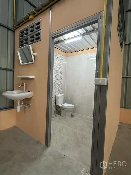 Warehouse for rent in Bueng Kum, Bangkok - Private restroom inside the warehouse featuring a toilet, sink, and tiled walls.
