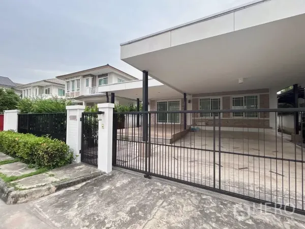 Detached House for sale in Bang Kapi, Bangkok - Angled exterior showing tiled porch, large canopy, and landscaped hedges at the front of the house.