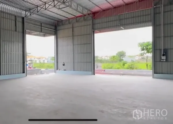 货栈 出租在Lam Luk Ka, Pathum Thani - 仓库内部空间开阔，钢结构高挑屋顶，宽阔开口与平整混凝土地面，面向绿地。