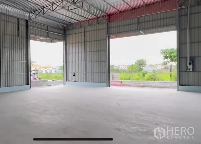 货栈 出租在Lam Luk Ka, Pathum Thani - 仓库内部空间开阔，钢结构高挑屋顶，宽阔开口与平整混凝土地面，面向绿地。