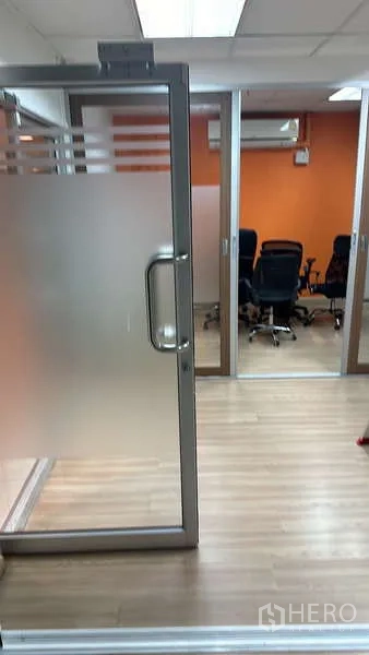 Office Space for rent - Frosted glass door to a conference room with an orange feature wall and seating.
