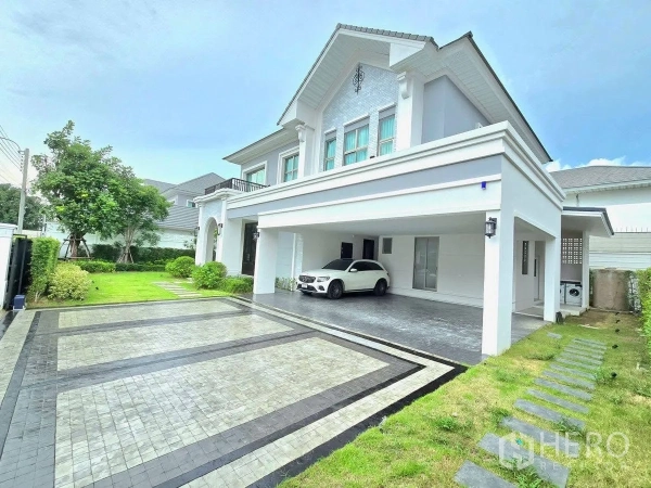 Detached House for rent or sale in Bang Phli, Samut Prakan - Front driveway of the house with wide paved area, covered carport and side lawn with stepping stones.