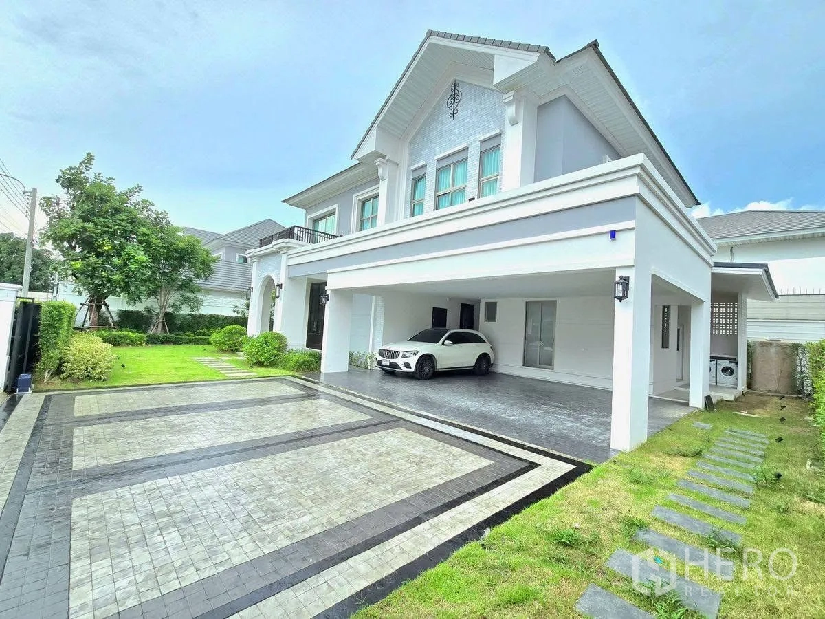 Detached House for rent or sale in Bang Phli, Samut Prakan - Front driveway of the house with wide paved area, covered carport and side lawn with stepping stones.