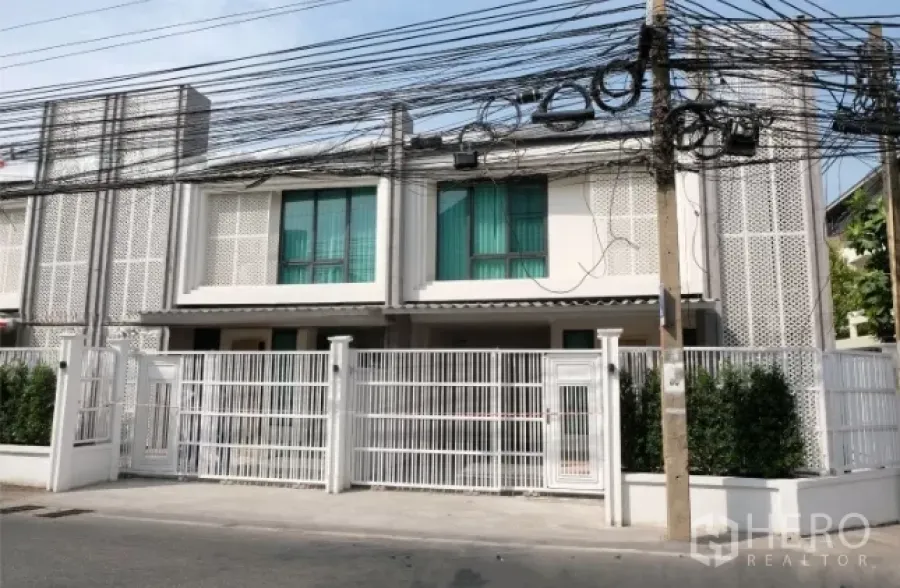 Townhouse for rent in Watthana, Bangkok - Modern two-storey townhouse facade with white metal fence on a quiet street in Watthana.