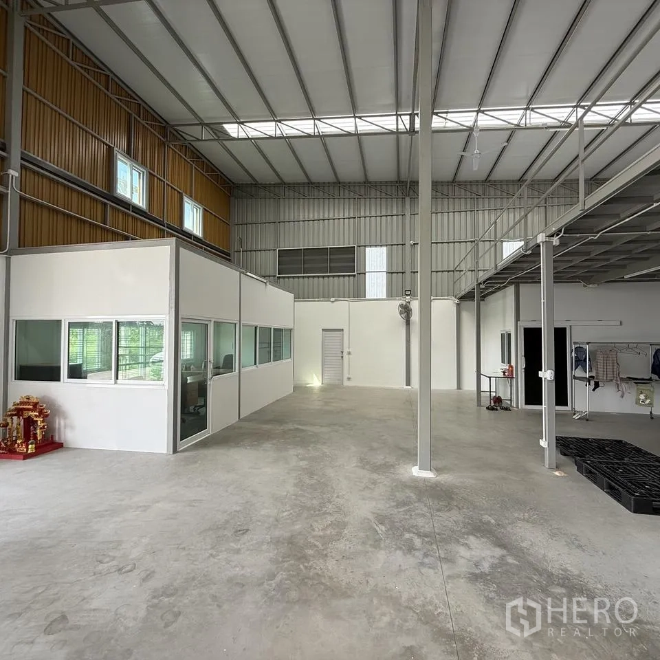 Warehouse for rent or sale in Khlong Luang, Pathum Thani - Warehouse interior showing high ceiling, internal office rooms and concrete floor.
