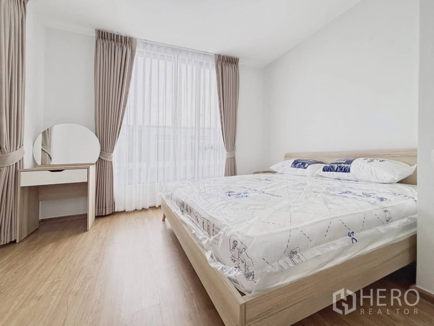 Townhouse for rent in Bang Phli, Samut Prakan - Master bedroom angle showing bed and wide windows dressed with curtains.
