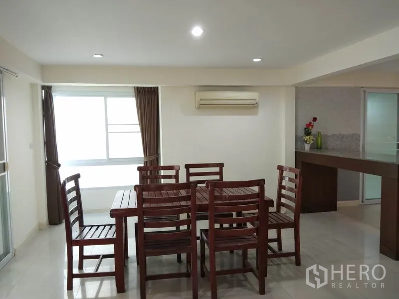 Detached House for rent in Watthana, Bangkok - Dining area with wooden table and chairs, air conditioning and a wide window.