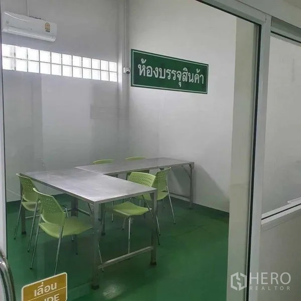 Factory for sale in Bang Pa-in, Phra Nakhon Si Ayutthaya - Packaging room with stainless work tables, green chairs and an air conditioner.