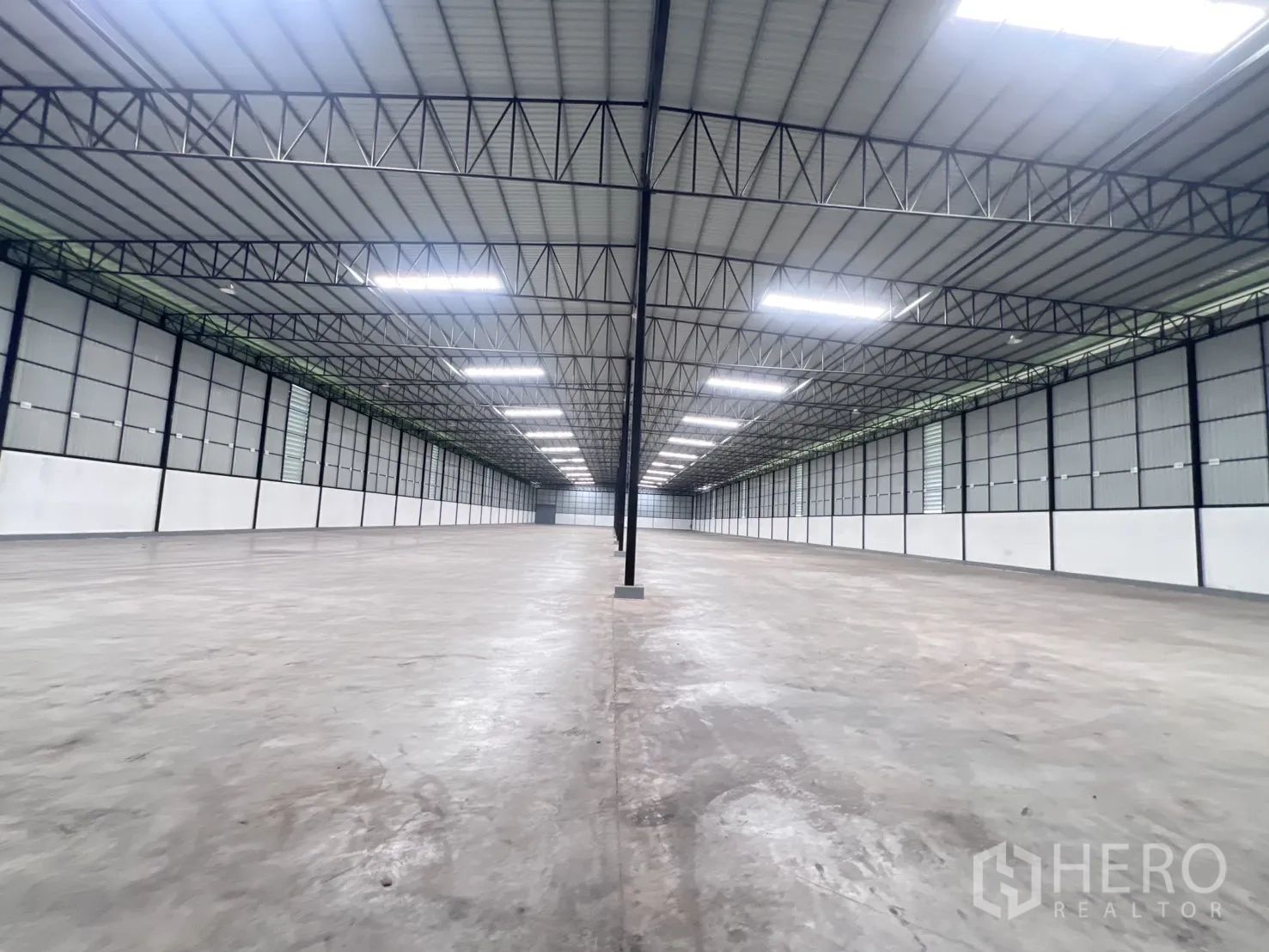 仓库 for rent in Mueang Samut Sakhon, Samut Sakhon - 从中央通道望向仓库深处，突出开阔空间与柱线。