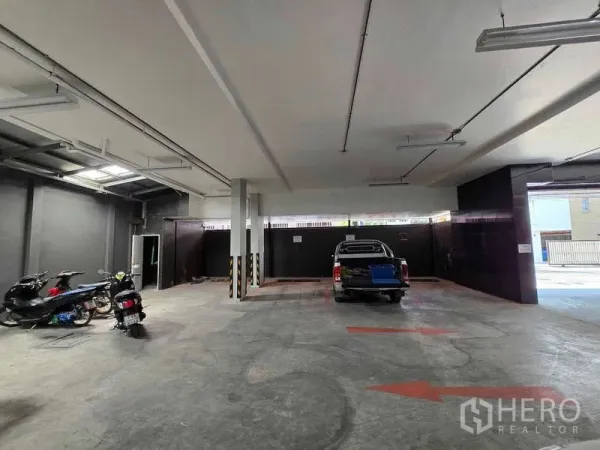 Retail Space for rent in Khlong Toei, Bangkok - Covered ground-floor parking and loading area with concrete floor, ceiling lights, motorcycles and a pickup truck.