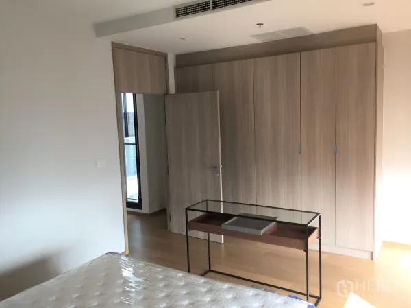 Condominium for rent in Pathum Wan, Bangkok - Bright bedroom featuring large built-in wardrobes and access to a balcony door.
