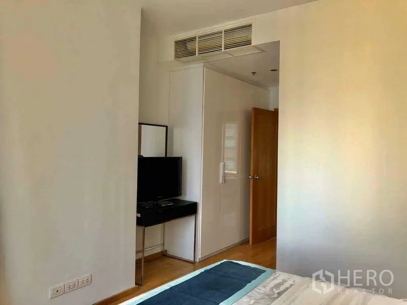Condominium for sale in Khlong Toei, Bangkok - Bedroom corner with built-in closet, wall-mounted TV and air-conditioning.