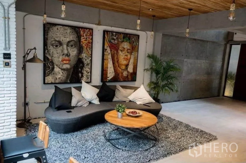 Townhouse for rent in Khlong Toei, Bangkok - Cozy lounge with curved sofa, coffee table, textured rug and large contemporary artwork.