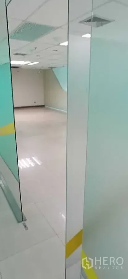 Office Space for rent in Huai Khwang, Bangkok - Empty office room viewed through a clear glass door with tile flooring and ceiling lights.