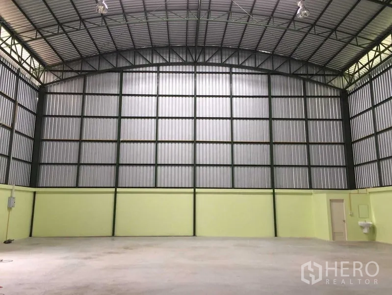 Warehouse for rent in Lat Krabang, Bangkok - Spacious warehouse interior with a high arched steel roof, concrete floor, utility sink and a small service room.