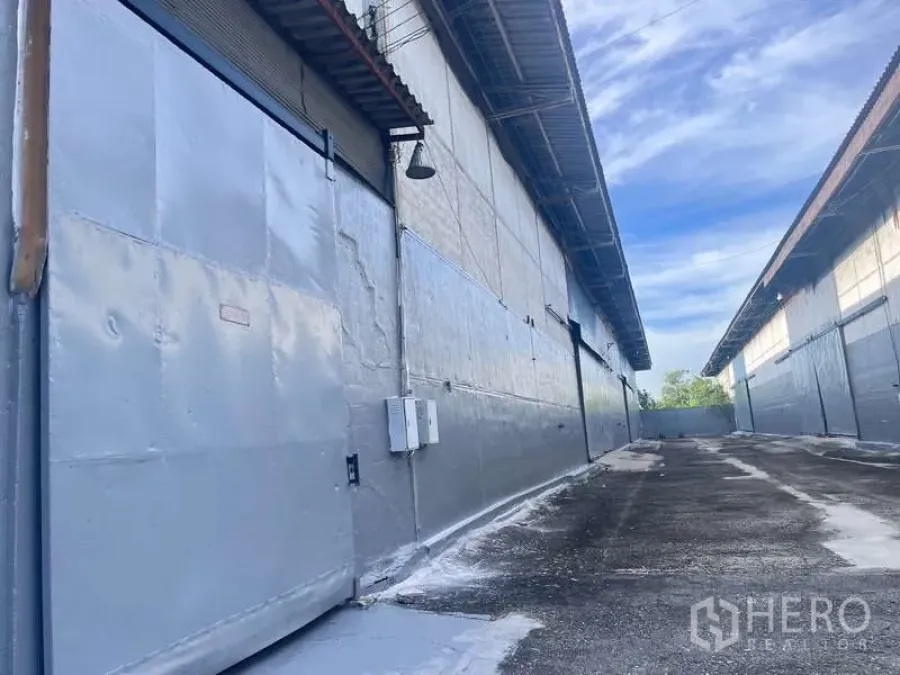 Factory for rent in Bang Pakong, Chachoengsao - Close-up of warehouse roller shutter door, electrical panels and access lane.