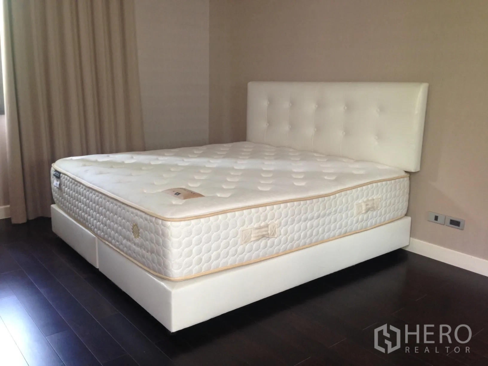Townhouse for rent in Bang Kapi, Bangkok - Bedroom featuring a large white upholstered bed, dark wood flooring and neutral walls.