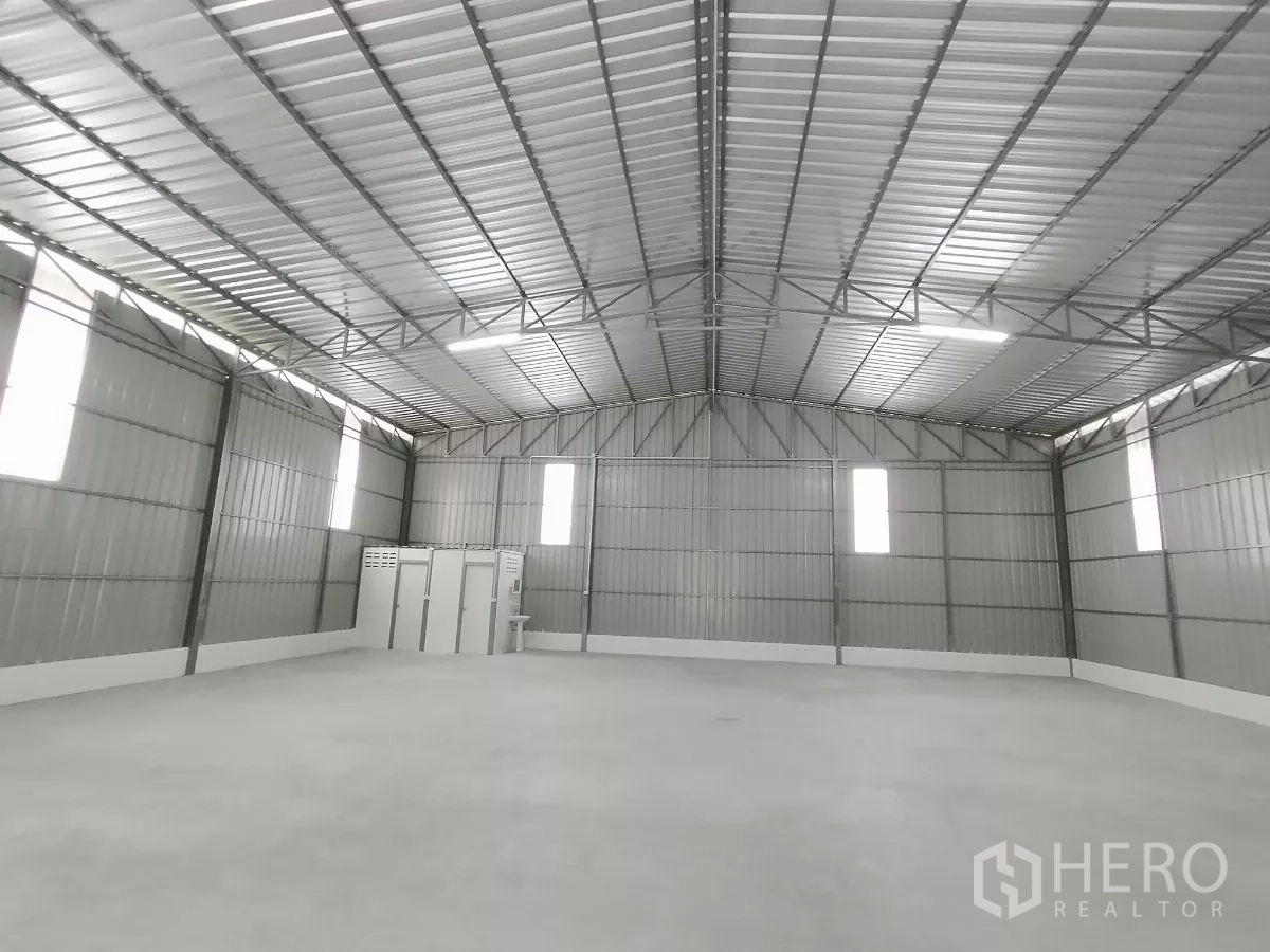 货栈 出租在Sai Mai, Bangkok - 仓库内部开阔，高钢结构屋顶，混凝土地面与竖向采光窗