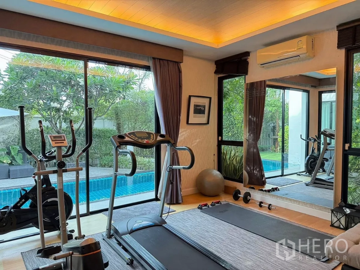 Detached House for rent or sale in Prawet, Bangkok - Home gym with cardio machines overlooking the private pool and garden.