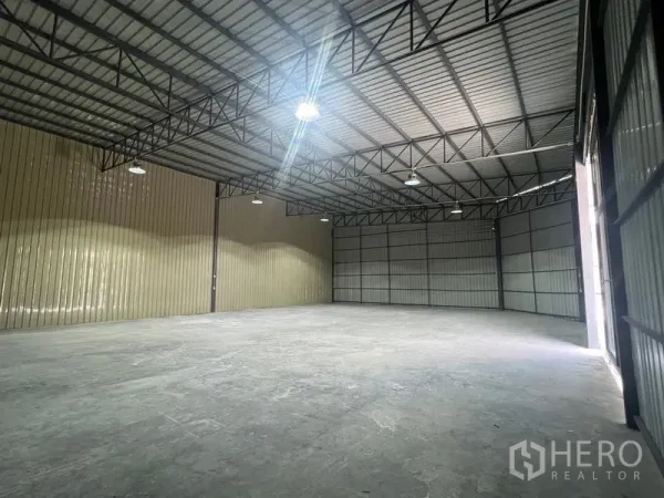 Warehouse for rent in Phra Khanong, Bangkok - Wide interior shot showing a large open floor plate, steel beams, and a sliding entry door.