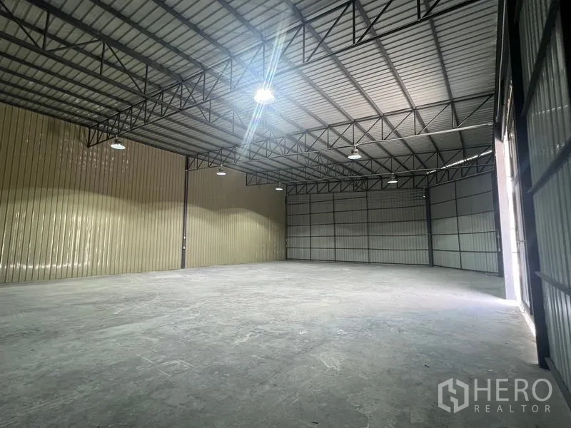 Warehouse for rent in Phra Khanong, Bangkok - Wide interior shot showing a large open floor plate, steel beams, and a sliding entry door.