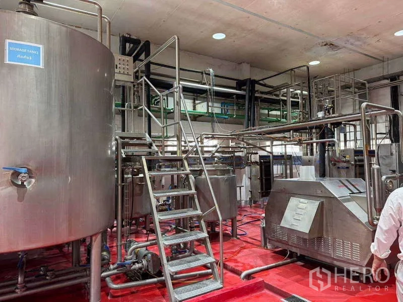 Factory for sale in Samut Prakan - Stainless platforms, stairs and interconnected pipes serving multiple processing machines.