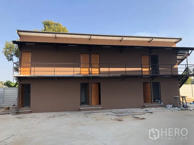 Factory for rent in Lam Luk Ka, Pathum Thani - Two-storey staff dormitory building with exterior walkway beside the factory compound.