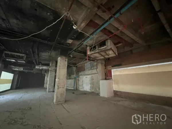 Retail Space for rent in Bang Rak, Bangkok - Wide rectangular retail area with utility lines and rough concrete walls.