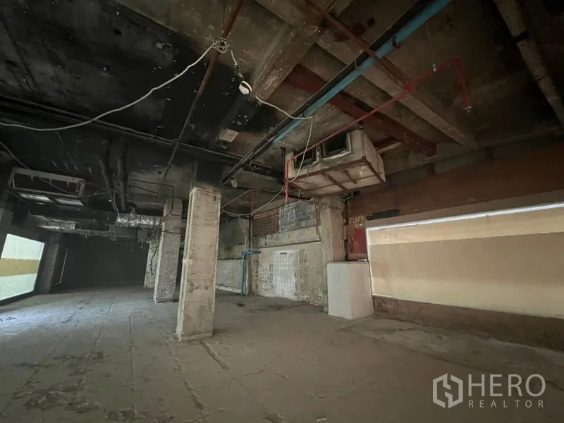 Retail Space for rent in Bang Rak, Bangkok - Wide rectangular retail area with utility lines and rough concrete walls.