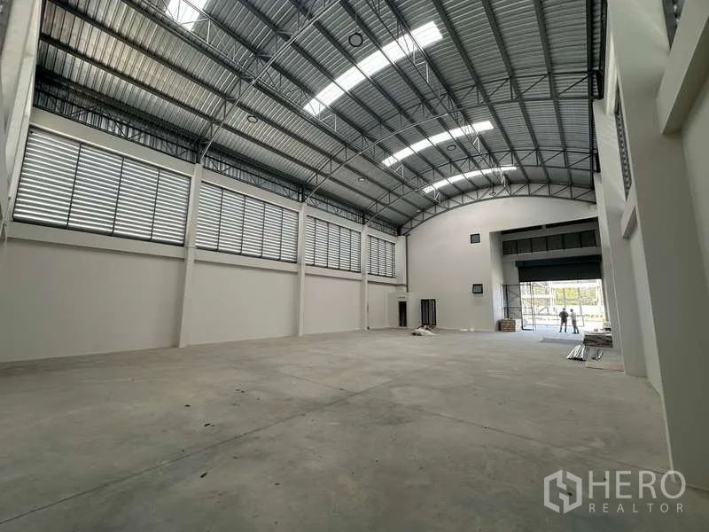 Factory for sale in Lam Luk Ka, Pathum Thani - Wide warehouse space with concrete floor, high roof and louvered ventilation along both sides.