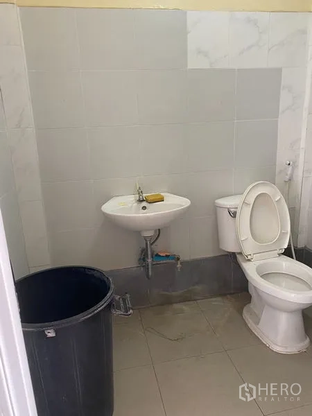 Shophouse for rent - Small tiled WC with wall-mounted basin and toilet.