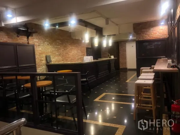 Shophouse for rent in Watthana, Bangkok - Restaurant bar interior with exposed brick walls, dark wood counter, pendant lighting and cafe seating.