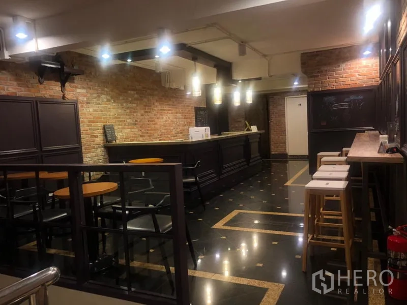 Shophouse for rent in Watthana, Bangkok - Restaurant bar interior with exposed brick walls, dark wood counter, pendant lighting and cafe seating.